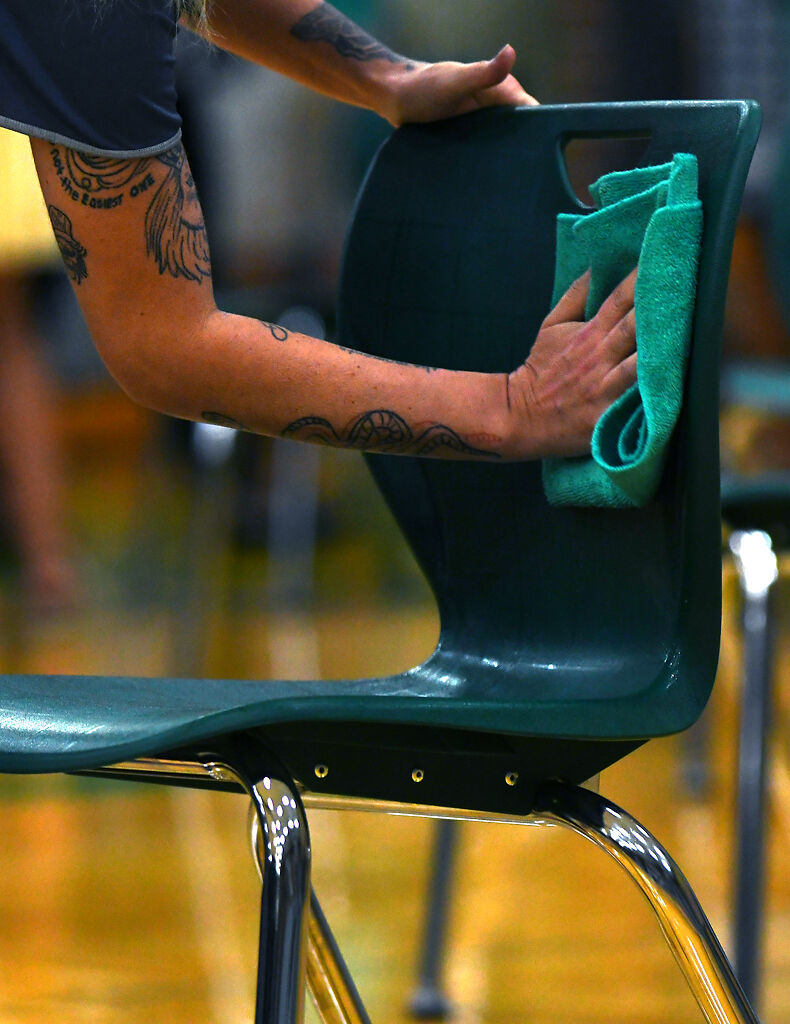 Staff members clean the chairs after the graduation ceremony Thursday